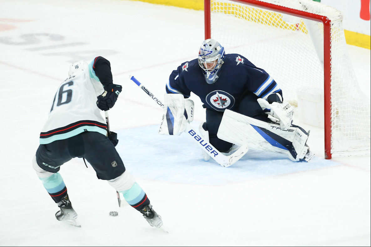 Hockey_NHL_Seattle Kraken forward Jared McCann and Winnipeg Jets goalie Eric Comrie